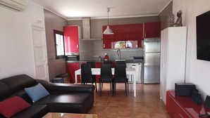 Um espaço compacto com cozinha compacta, área de refeições e sala de estar com sofá e mesa de centro.