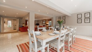 A spacious dining area with a wooden table set for six, surrounded by white chairs. - The Little House, Brancaster, Norfolk (Brancaster)