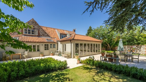 A house with a covered patio, a stone wall, and a well-maintained garden. - The Little House, Brancaster, Norfolk (Brancaster)