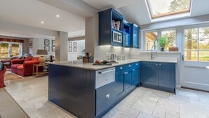 A modern kitchen with dark blue cabinets, a central island, and a skylight. - The Little House, Brancaster, Norfolk (Brancaster)