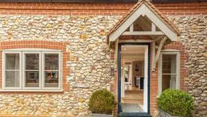 A stone facade with a brick entrance, a sign reading "BEACH," and two potted plants. - The Little House, Brancaster, Norfolk (Brancaster)