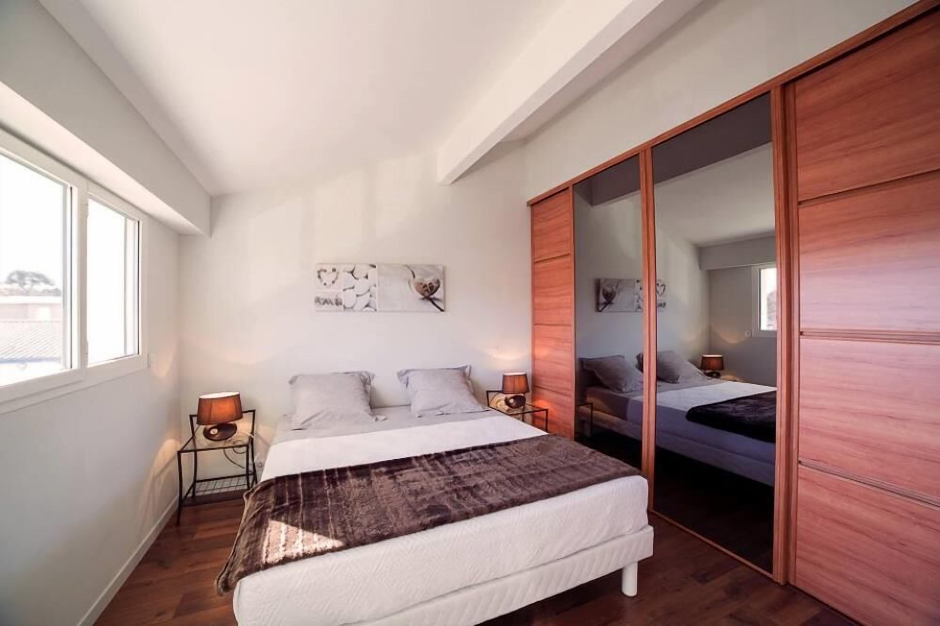 Ein Schlafzimmer mit einem Bett, Nachttischen, einem Spiegel und einem Schiebetürenschrank.