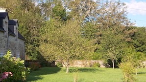 Une maison en pierre avec un toit en pente et une pelouse bien entretenue.