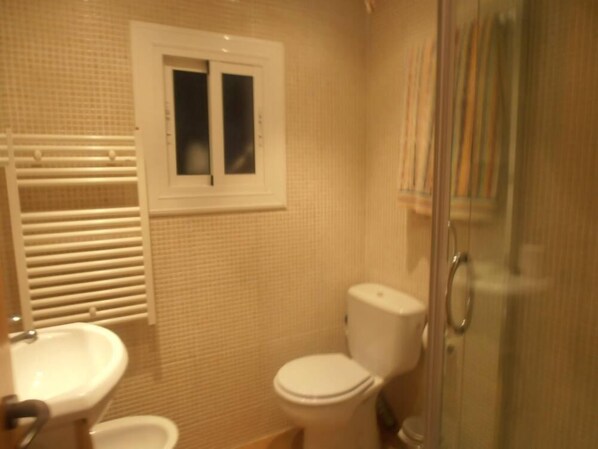 A bathroom with a toilet, sink, and a window.