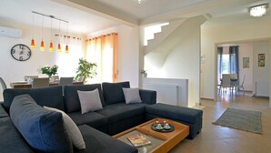 A modern living room with a sectional sofa, a coffee table with magazines, and a staircase leading to another room. - Villa Amaryllis is the ultimate booking option for couples, families and friends (Corfu)
