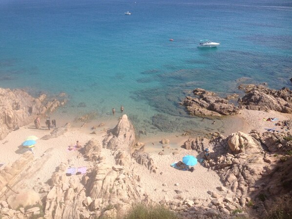 A rocky beach with clear blue water, a few people, and boats. - VILLA, 200 m from Bodri BEACH, close to sea view, air-conditioning, large landscaped PARK, (Corbara)