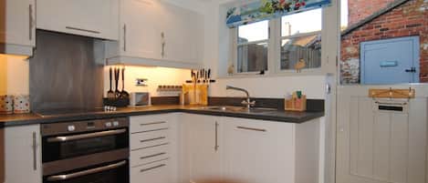 A kitchen with white cabinets, stainless steel appliances, and a window with a view of a brick wall.