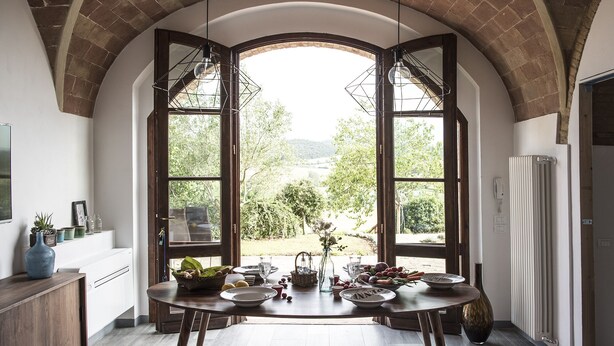 A dining area with a table set for four, a large window with an arched ceiling, and a view of the outdoors. - La Casetta, Casole d'Elsa, Siena. Join the real Tuscany countryside! (casole d'elsa siena)