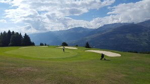 Un parcours de golf offrant une vue dégagée sur les montagnes en arrière-plan.