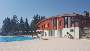 Un espace piscine avec un bâtiment portant l’inscription « LA PISCINE » et un mur en pierre.