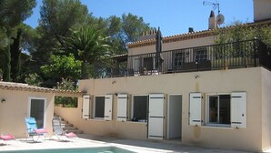 Ein zweistöckiges Gebäude mit Schwimmbad, Sitzgelegenheiten im Freien und einem Balkon.
