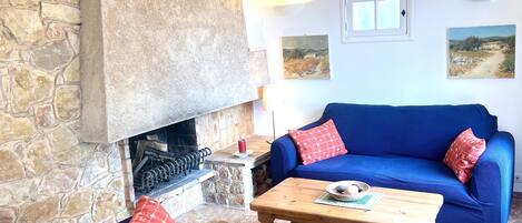 A cozy living room with a stone fireplace, a blue sofa set, and a wooden coffee table.