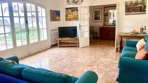 Ein Wohnzimmer mit Fernseher, Salons in Türkis, einem Kronleuchter und Blick durch große Fenster.