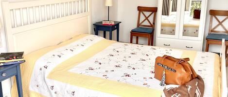 A bedroom with a bed, a nightstand, a chair, a wardrobe, and a window.