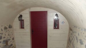 En rød dør med et lille vindue over, omkranset af to vægmonterede lanterner.