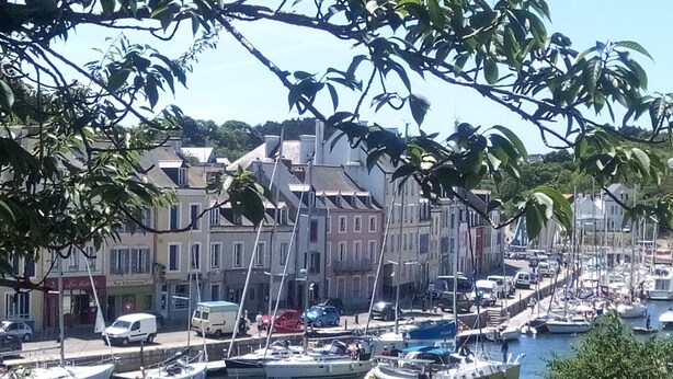 Un port de plaisance avec des bateaux amarrés, une promenade en bord de mer et des bâtiments le long de la côte.