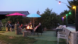 An outdoor seating area with stone tables and chairs, a fire pit, and string lights. - House / Villa - St rémy le petit (Saint-Remy-Le-Petit)