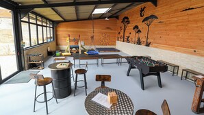 A room with a foosball table, a climbing wall, and a slide. There are also several stools and a table with a menu. - House / Villa - St rémy le petit (Saint-Remy-Le-Petit)