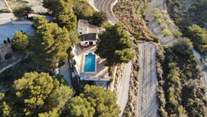 Un paisaje escalonado con una casa que tiene piscina, rodeada de árboles y vegetación.