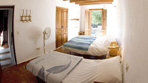 Un dormitorio con cama, ventilador, puerta de madera y ventana.