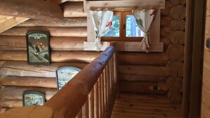 Ein Holzblock-Interieur mit einer Holztreppe, einem Fenster mit Vorhängen und einem Schild an der Wand.