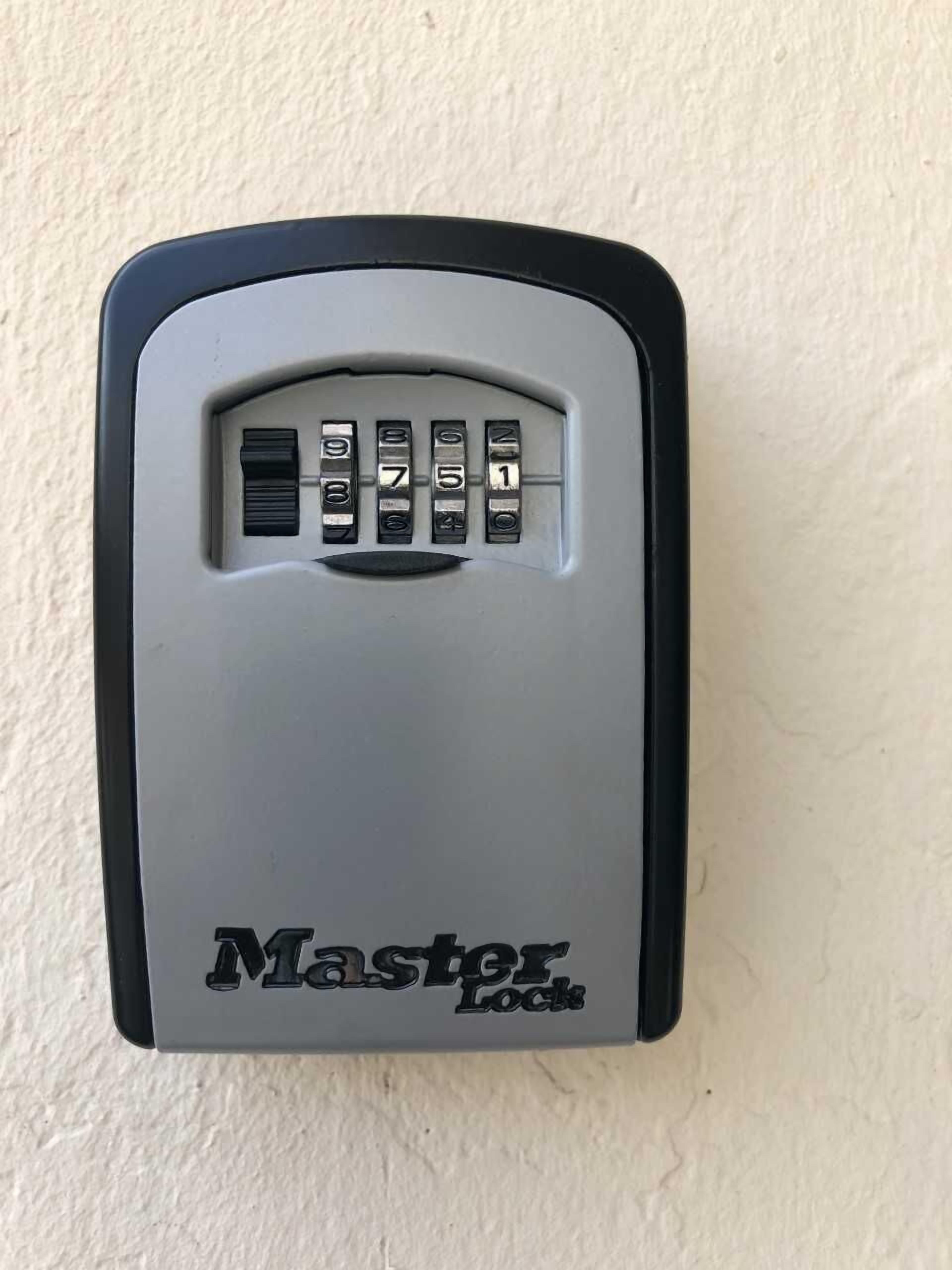 Een combinatiecijferlot van Master Lock bevestigd aan een muur.