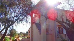 A building with a staircase leading to a balcony, surrounded by trees and potted plants. - Son Antem, Air Conditioning, Wifi free, Private pool, 8 km From Cala Blava (Llucmajor)