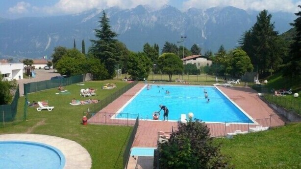 A swimming pool surrounded by a grassy area with a mountain view in the background.