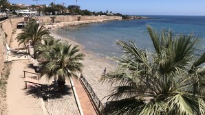Una spiaggia con una passeggiata sabbiosa, palme e un mare blu cristallino.