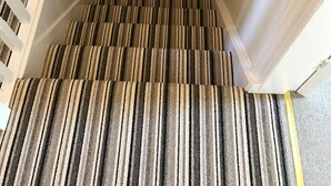 A staircase with striped carpet and white walls.