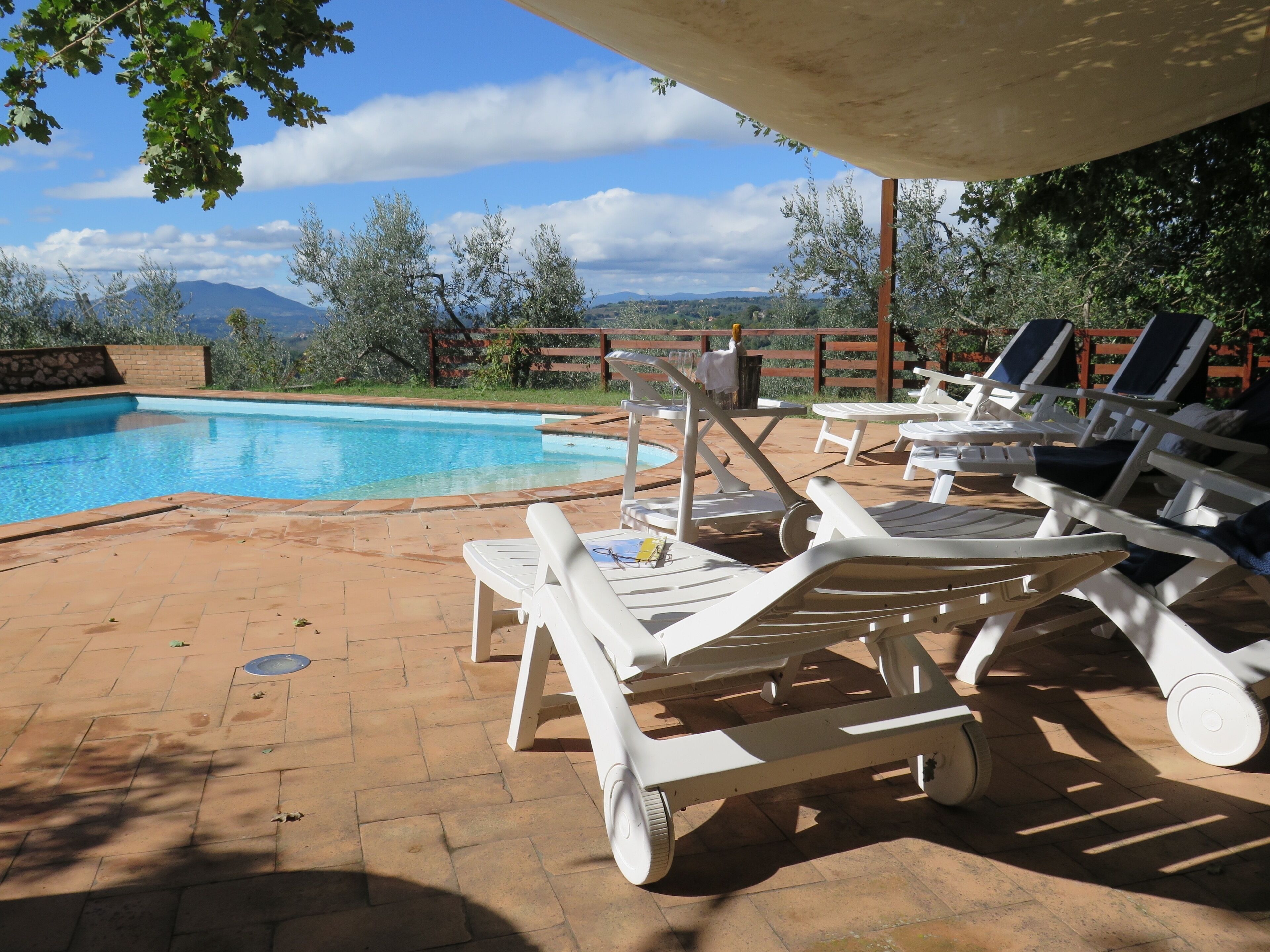 A poolside area with lounge chairs and a view of mountains.