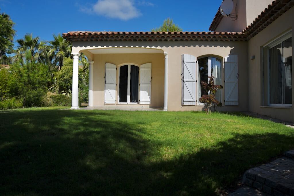 Una casa amb un porxo cobert, un teulat de rajola i un jardí ben cuidat.