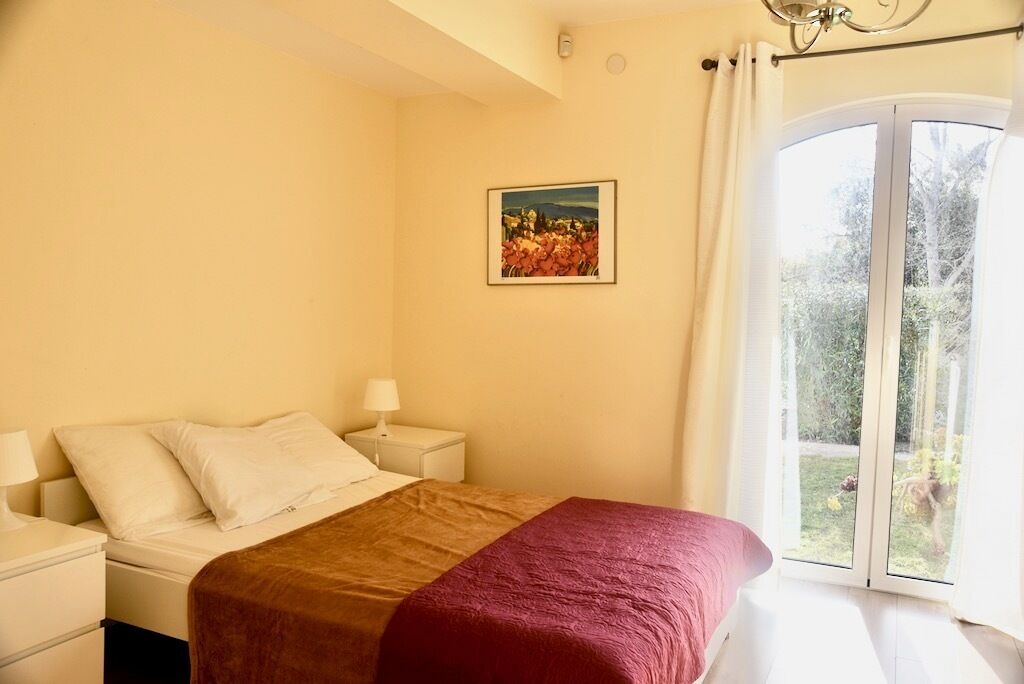 Un dormitorio con cama, mesita de noche, lámpara y un cuadro en la pared.