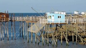 Une jetée dotée de plusieurs structures en bois, notamment une petite cabane et un bâtiment plus grand, qui s’avance dans l’eau.