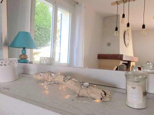 A room with a wooden table, a lamp, a candle, and a window with curtains.