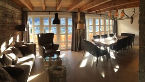 Ein gemütliches Wohnzimmer mit einer Couch, einem Glastisch und einem Essbereich mit großem Tisch und Stühlen.