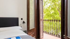 A hotel room with a bed, a nightstand, a window, and a balcony with a metal railing. - CASANOVA ELEGANCE, excellent apartment, excellent location in Barcelona center (Barcelona)