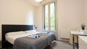 A modern bedroom with a large bed, a desk, and a window with a view of trees. - CASANOVA ELEGANCE, excellent apartment, excellent location in Barcelona center (Barcelona)