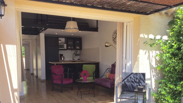 Un espacio de sala-comedor abierto con piso de madera, una mesa de comedor y varias sillas. Se ve un área de cocina al fondo.