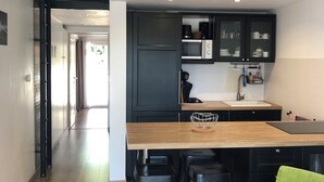 Una cocina moderna con armarios oscuros, una isla de madera y una lámpara colgante.