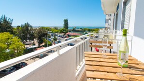 A balcony with a wooden table, a bottle of white wine, and a glass. - Fuzeta beach apartment 1 - Free Wifi (Olhao)