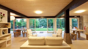 A spacious living area with a wooden ceiling, large windows, a white sofa, and a dining table with chairs. - House with pool 8 minutes from the beach, free wifi (Ea)