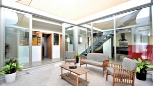 Un intérieur moderne avec des murs en verre, une table basse en bois et deux fauteuils en osier.