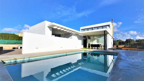 Une maison moderne dotée d’une piscine, de grandes fenêtres et d’un toit plat.