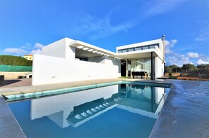 A modern house with a swimming pool, large windows, and a flat roof.