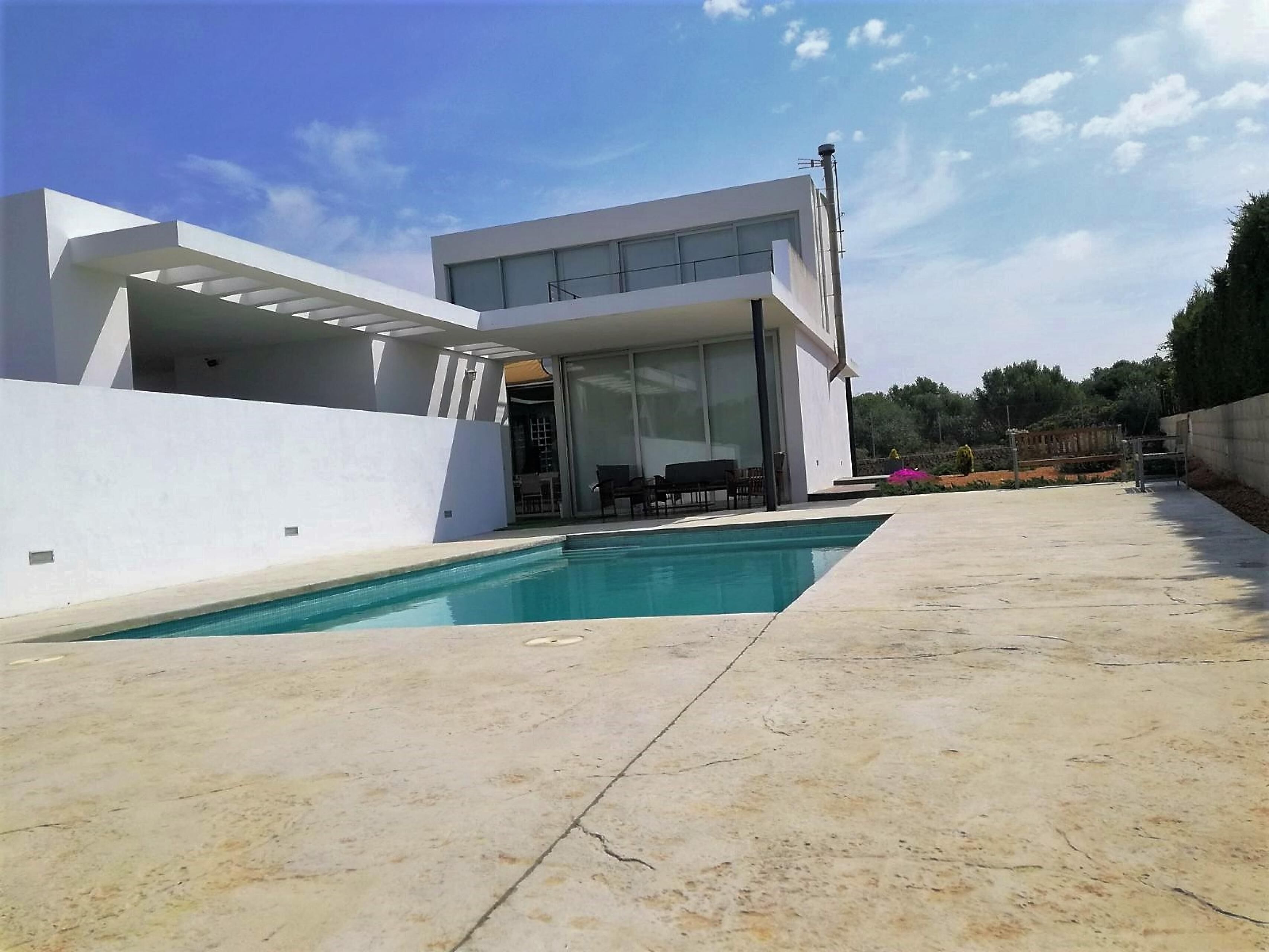 A modern house with a swimming pool, large windows, and a patio area.