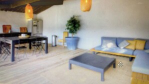 Una habitación con cama, mesa, sillas y una lámpara colgante.