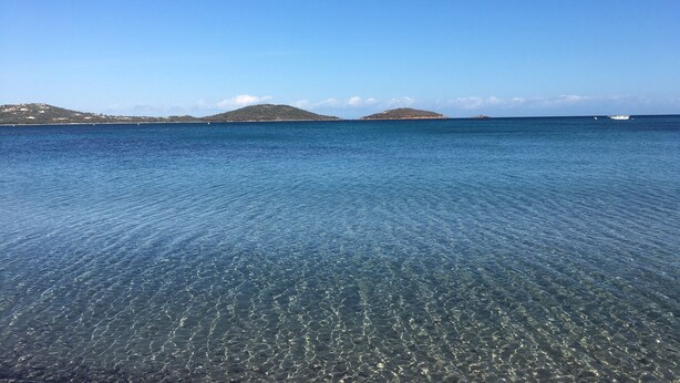 Una vista despejada de un mar tranquilo con dos islas pequeñas a lo lejos.