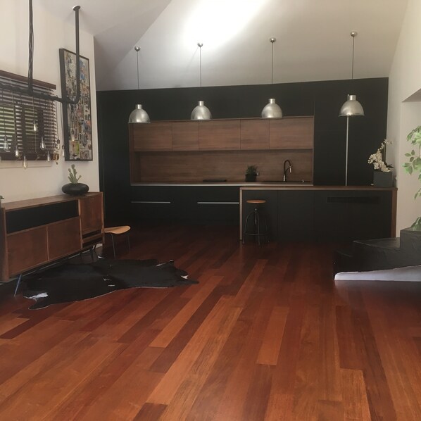 A modern kitchen with wooden cabinets, pendant lights, and a black rug on the floor. - Large 320m2 villa, fully air-conditioned, heated swimming pool, 5000m2 enclosed garden (Ste Lucie de Porto Vecchio)