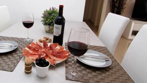 A dining table set with plates, cutlery, a bottle of wine, and a bowl of olives.